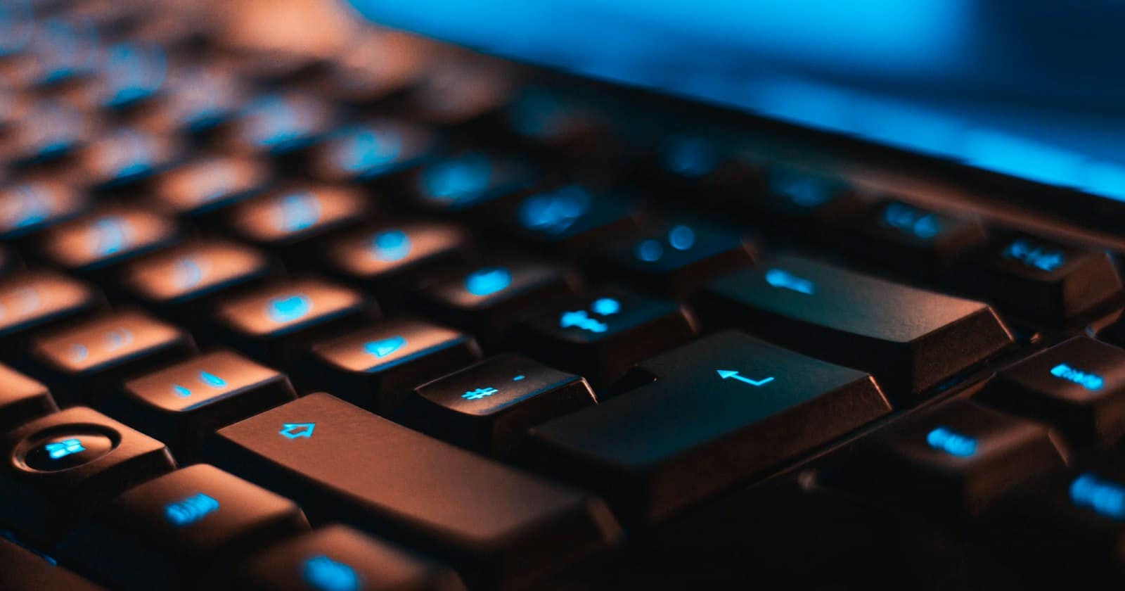 Hands typing on a keyboard in a dimly lit workspace
