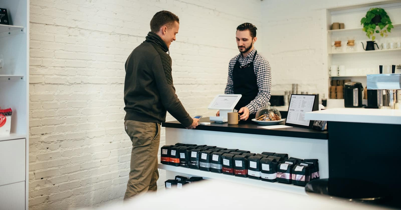 A shop owner checking a returning customer's order history on a phone while preparing a repeat order
