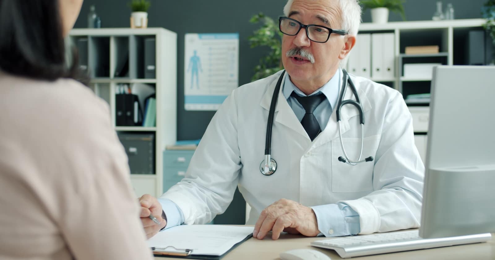 Der Empfang einer Arztpraxis, an dem das Telefon klingelt, während das Team Patienten betreut.