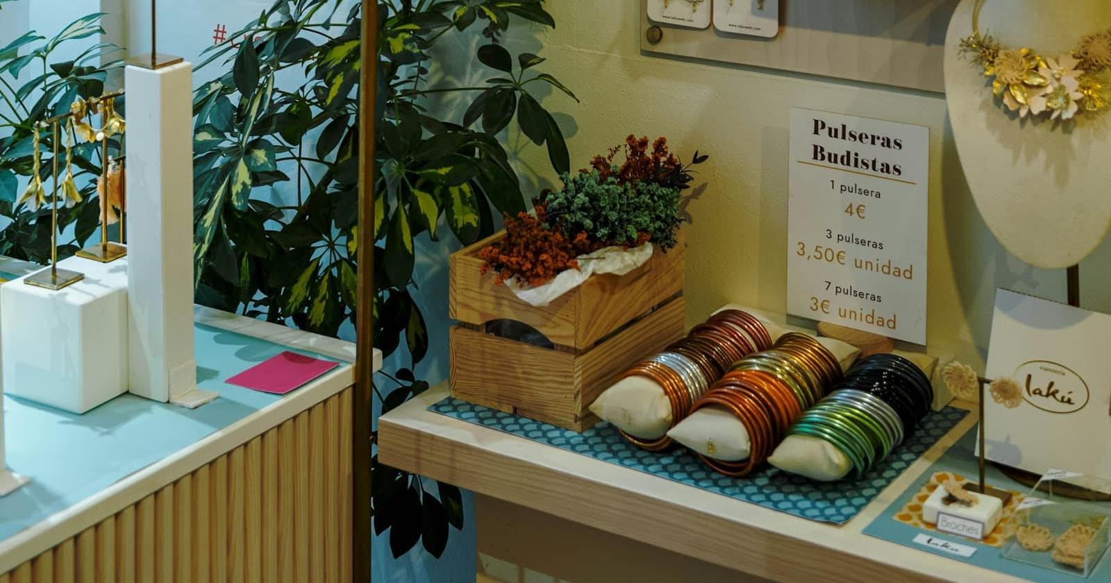 Eine Ladeninhaberin hält ein Smartphone mit einer Produktliste in der Hand, hinter ihr die Regale mit denselben Produkten.