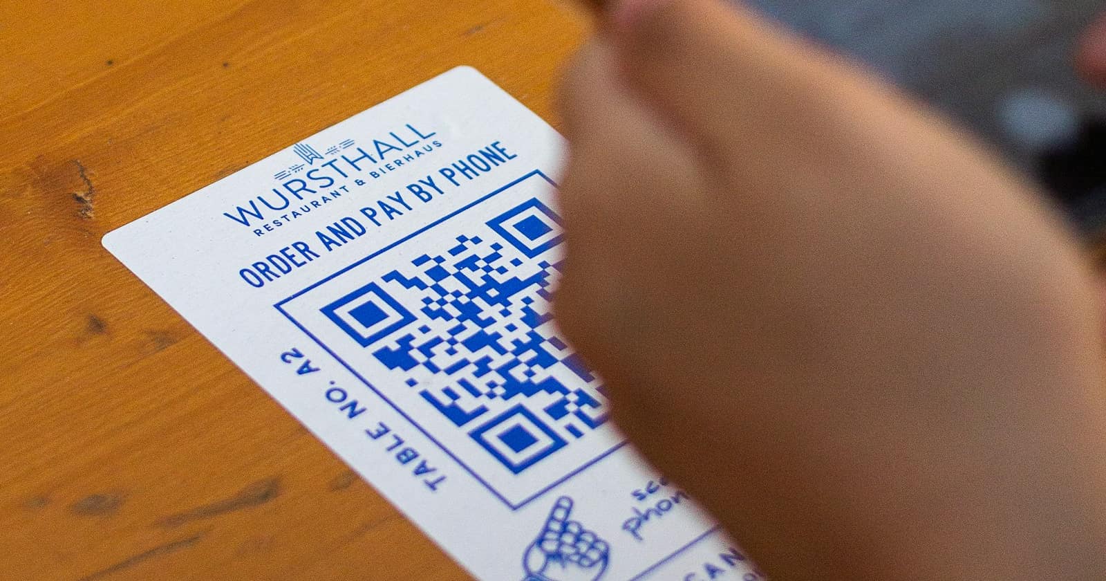 A customer scanning a QR code on a printed card with a smartphone inside a shop.